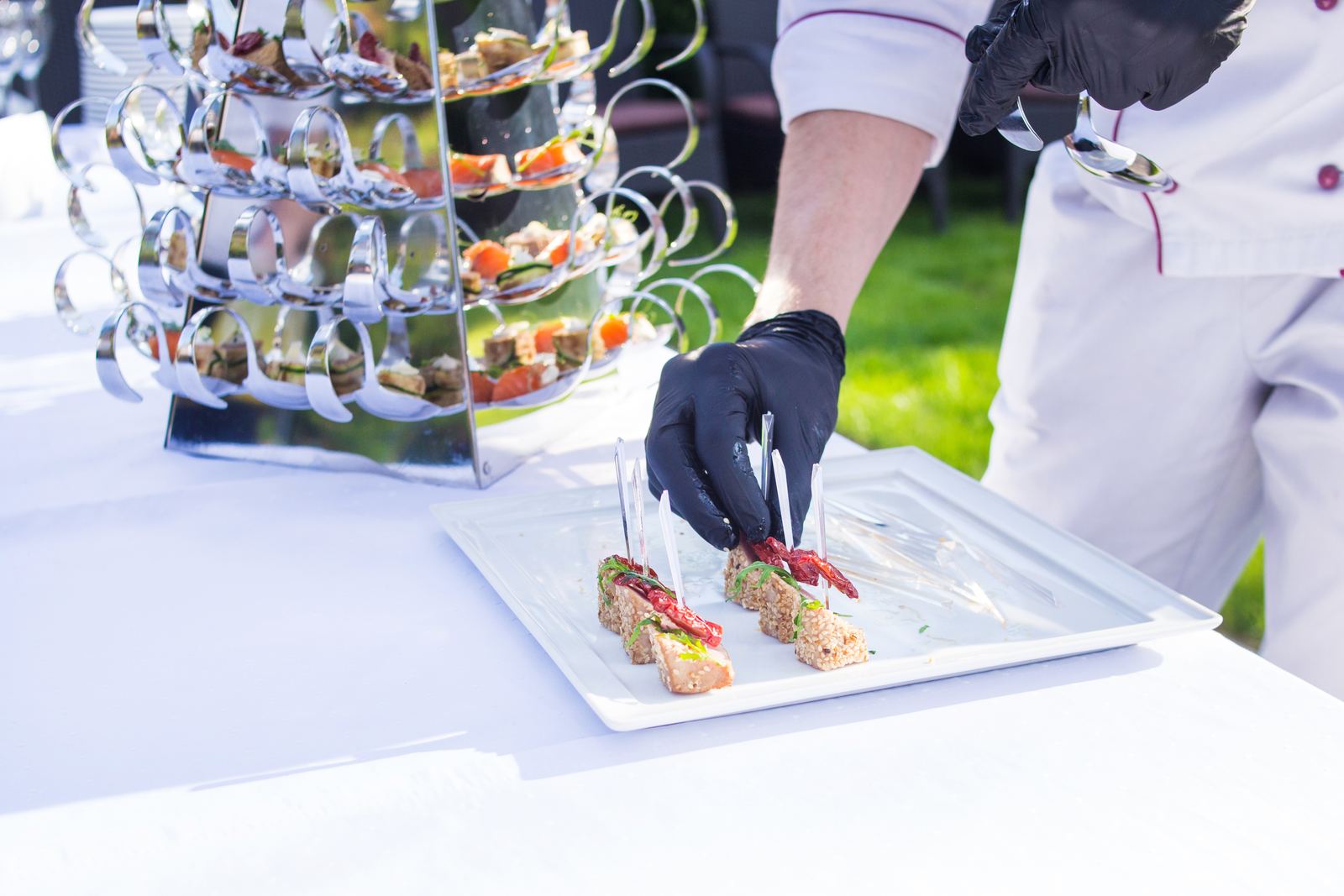 Chef legt met zorg fijne hapjes op een schaal tijdens een buitenevenement